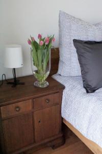 een vaas met roze bloemen op een nachtkastje naast een bed bij Ferienwohnung Storchennest in Bad Rothenfelde