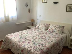 a bedroom with a bed with a floral comforter at Urbanizacion primera línea de playa in Denia