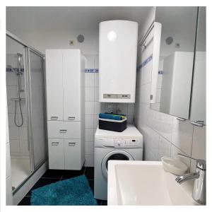 baño blanco con lavadora y lavamanos en Ingrid’s Guesthouse Spittal, en Spittal an der Drau