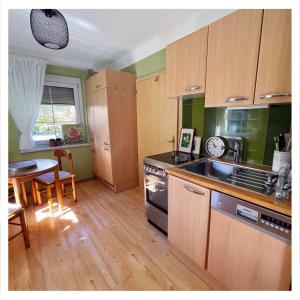 - une cuisine avec des placards en bois, une table et une cuisinière dans l'établissement Ingrid’s Guesthouse Spittal, à Spittal an der Drau