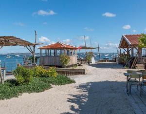 uma praia com algumas mesas e edifícios e o oceano em Mobil home climatisé au calme et proche des activités LEGE CAP FERRET em Lège-Cap-Ferret