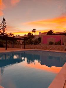 a swimming pool with a sunset in the background at Aurora Sol in Luz