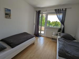 a bedroom with two beds and a large window at Feldberg Appartement in Neu-Anspach