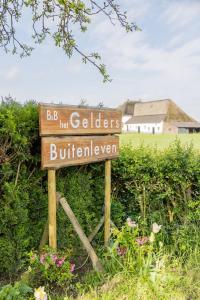 un panneau dans un champ avec une maison en arrière-plan dans l'établissement Het Gelders Buitenleven, à Overasselt