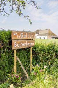 una señal en un campo con una casa en el fondo en Het Gelders Buitenleven, en Overasselt