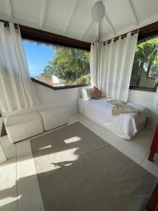 Un dormitorio con una cama y una ventana grande. en Casa Delfi, Hermosa vista, Jacuzzi e Praia , Buzios, en Búzios