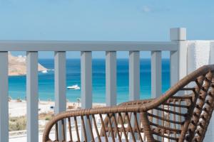 a wooden bench sitting on a balcony overlooking the ocean at Penelope Village in Kalo Livadi