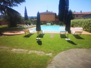 une cour avec des chaises et des parasols ainsi qu'une piscine dans l'établissement Villa Al Piano, à Lastra a Signa