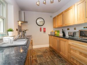 a kitchen with wooden cabinets and a clock on the wall at Meadowbank Cottage in Carnforth