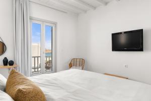 a bedroom with a bed and a tv and a balcony at Penelope Village in Kalo Livadi