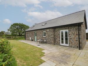 a stone cottage with a patio in front of it at Ystabl Robyn in Carmarthen