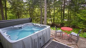 - un bain à remous sur une terrasse avec une table et une chaise dans l'établissement Secluded Streamside Home with Hot Tub, à Margaretville