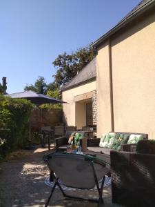een patio met een bank, een tafel en een parasol bij Gîte de la Cuve in Huisnes-sur-Mer