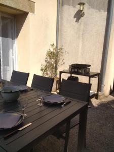 een houten tafel met borden en glazen erop bij Gîte de la Cuve in Huisnes-sur-Mer