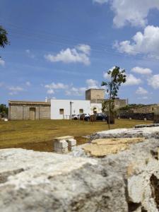 a white building with a car parked in a field at Masseria Petrore Grande di Polimeno Alessandra in Cutrofiano