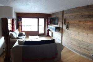 een woonkamer met een bank en een houten muur bij Mon refuge face au Mont Blanc in Saint-Gervais-les-Bains