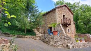 Cette maison en pierre dispose d'un balcon et d'un mur en pierre. dans l'établissement Gîtes la Molière Haute, à Plaisance