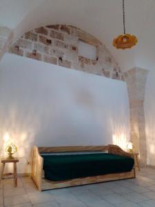 a bedroom with a green bed against a wall at Masseria Petrore Grande di Polimeno Alessandra in Cutrofiano