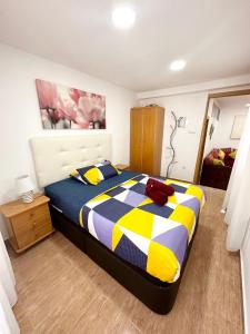 a bedroom with a bed with a yellow and blue comforter at Apartment en Rambla in Alicante +22 photos