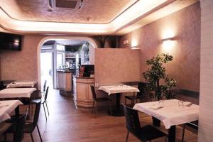 a restaurant with tables and chairs and a kitchen at Rooms Don Alfonso in Parma