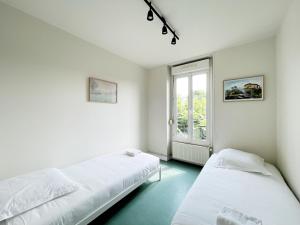 two beds in a white room with a window at Relais Touraine Sologne in Noyers-sur-Cher