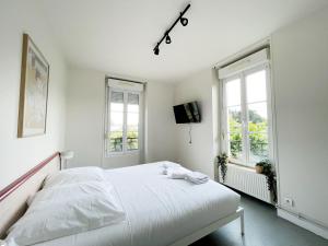 a white bedroom with a bed and two windows at Relais Touraine Sologne in Noyers-sur-Cher