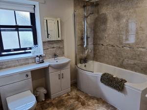 a bathroom with a sink and a tub and a toilet at Cosy cottage in the heart of Pateley Bridge. in Pateley Bridge
