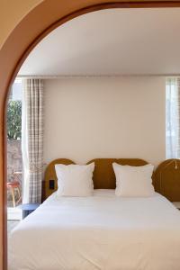 um quarto com uma cama com lençóis brancos e uma janela em Hotel Saint Julien em Biarritz
