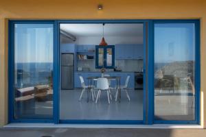 a kitchen with blue doors and a table and chairs at Elpida - breathtaking view in Mochlos