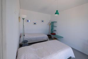 Cette chambre blanche comprend 2 lits et une étagère bleue. dans l'établissement Elpida - breathtaking view, à Mochlos
