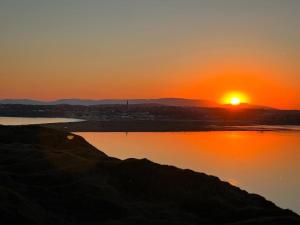 una puesta de sol sobre un cuerpo de agua con la puesta de sol en 3 Bed town house 10 min from beach en Tramore