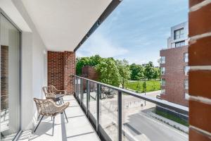 balkon z 2 krzesłami i widokiem na budynek w obiekcie Angielska Grobla Apartments w Gdańsku