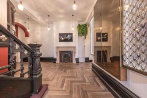 a hallway with a fireplace and a staircase with wood floors at The Pocklington - The Golden Mile Suite in Leicester