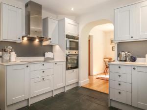 a kitchen with white cabinets and an archway at High Stile in Keswick