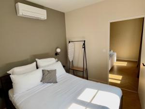 a bedroom with a bed with white sheets and a fan at Legend - Parking privé - Gare - Centre ville - Quai de Saône - fibre in Mâcon +8 photos
