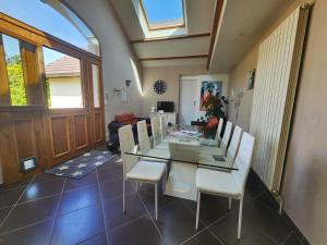 a dining room with a glass table and white chairs at Maison de campagne dans le vignoble champenois 