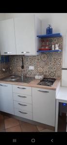 a kitchen with white cabinets and a sink and a stove at il colibri' in Procida