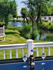 two wine glasses sitting on a table on a balcony at Lake Escape - Hoburne Cotswolds in South Cerney