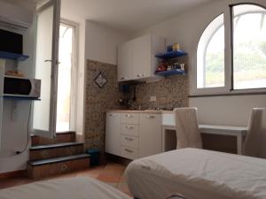 a kitchen with white cabinets and a bed in a room at il colibri' in Procida
