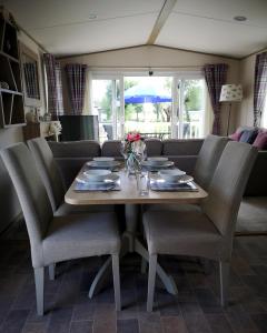 a dining room table with chairs and a couch at Lake Escape - Hoburne Cotswolds in South Cerney
