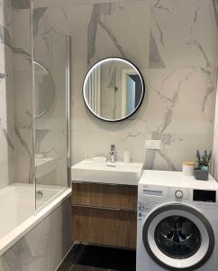 a bathroom with a washing machine and a mirror at Apartamenty 48 Scala in Gdańsk