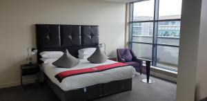 Brooklands Hotel & Spa في يبريدج: غرفة نوم مع سرير مع اللوح الأمامي الأسود ونافذة