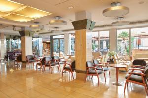 un restaurante con sillas, mesas y ventanas en Invisa Hotel La Cala en Santa Eulalia del Río