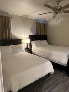 two beds in a hotel room with a ceiling fan at Brand New Cute Home in Odessa near Midland in Odessa