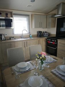 una cocina con una mesa con platos y flores. en Lake Escape - Hoburne Cotswolds, en South Cerney