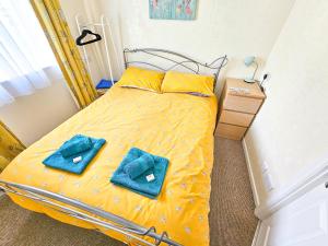 a bedroom with a yellow bed with blue towels on it at Dart Haven - cheerful holiday bungalow in Galmpton in Galmpton-on-the-Dart