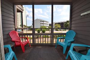three chairs sitting on a porch with a view of a building at Sweet Caroline Remodeled with Partial Ocean View and Oceanfront Pool in Myrtle Beach