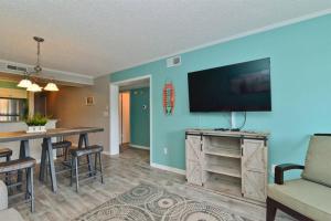 a living room with a flat screen tv on a wall at Sweet Caroline Remodeled with Partial Ocean View and Oceanfront Pool in Myrtle Beach