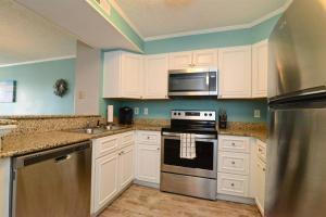 a kitchen with white cabinets and stainless steel appliances at Sweet Caroline Remodeled with Partial Ocean View and Oceanfront Pool in Myrtle Beach