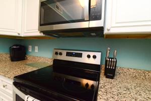a kitchen with a stove and a microwave at Sweet Caroline Remodeled with Partial Ocean View and Oceanfront Pool in Myrtle Beach